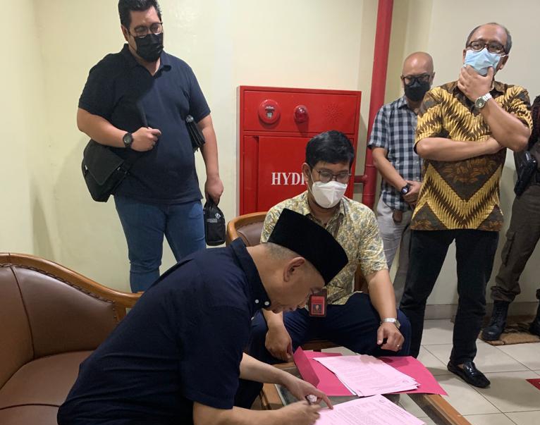 Tersangka RARL berbaju hitam pakai peci sedang menandatangani surat penahanannya (Foto : Puspen Kejagung)